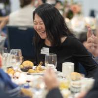 Woman laughing while conversing with others at her table